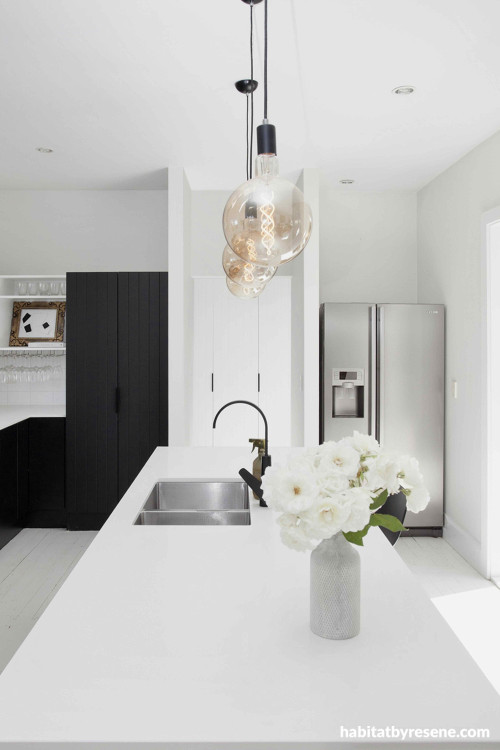 The heart of the home is a dreamy scene. The kitchen is bright and welcoming with Resene Black White on walls and ceiling, with trims in Resene Alabaster. Contrasting dark cabinetry and fixtures provide continuity from the exterior, creating a neutral hom