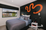 Feature wall painted in black colour topped with zesty orange pattern completes the room