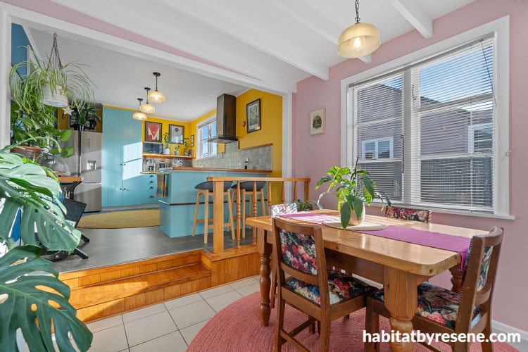 Dining room featuring soft pink walls and kitchen featuring bright yellow walls and soft blue cabinetry