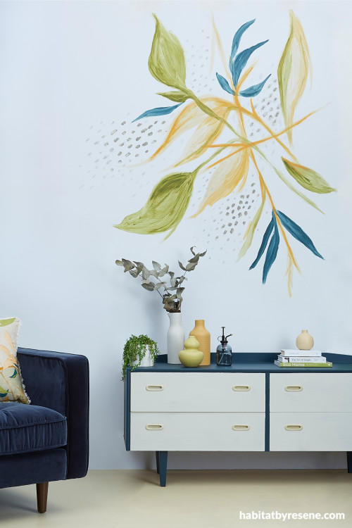 a flower mural on a blue wall with drawers and a chair
