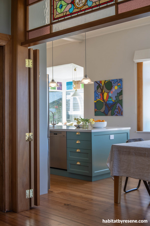 The rimu features are finished in Resene Aquaclear and the stain glass window pay homage to this heritage home. The kitchen island is painted in Resene Cutty Sark and walls in Resene White Pointer.  