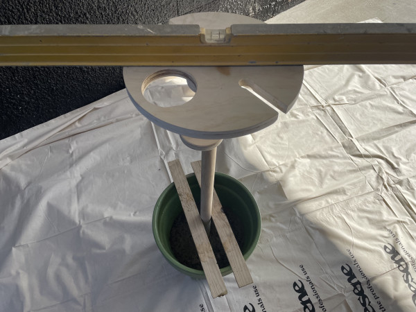 A plant pot with concrete and a wine holder standing in it