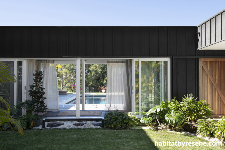 House nestled in lush greenery painted in black and white