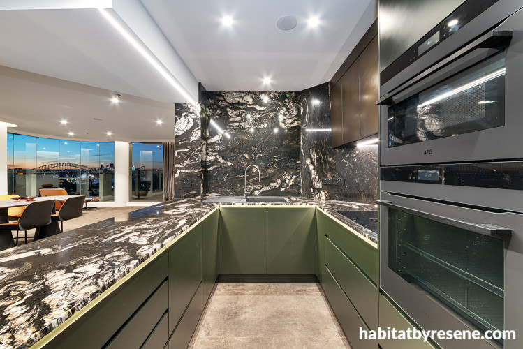 Kitchen with marble walls and benchtops and cabinets painted in Resene Midnight Moss