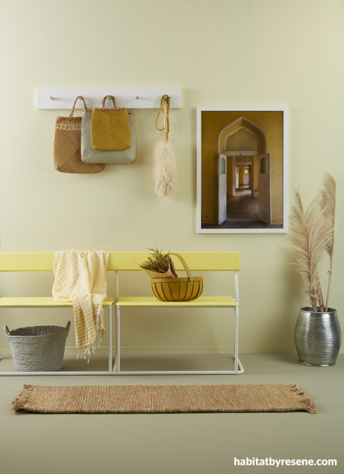 A yellow entry with a bench seat and wall hooks