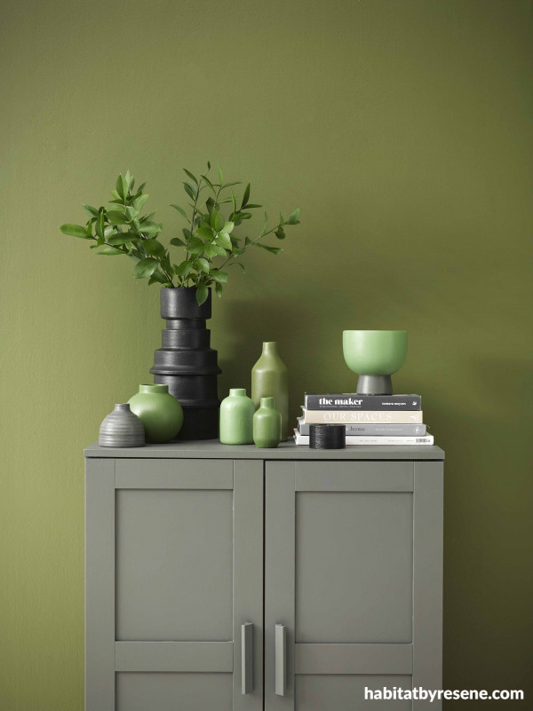 In this earthy green space, the wall is painted in Resene Waiouru, cabinet in Resene Gravel, tall vase and tealight holder in Resene Black.