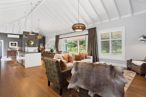 white lounge, white living room, open plan living, high ceiling, exposed rafters, timber flooring