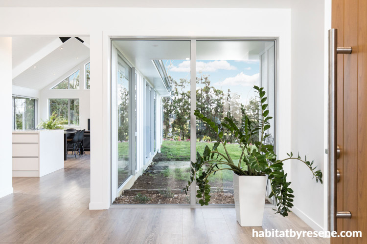 entranceway, wood front door, indoor plant, white living area, white house 