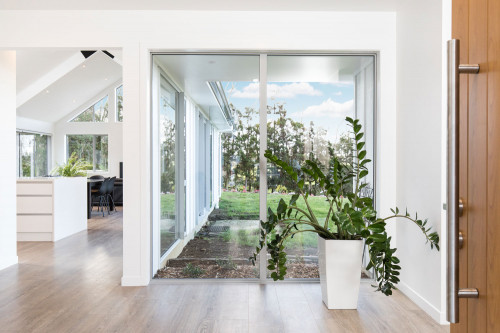entranceway, wood front door, indoor plant, white living area, white house