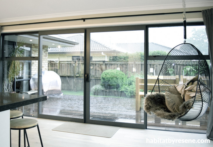 indoor outdoor flow, kitchen, living area, neutral dining room, deck, indoor hanging chair 