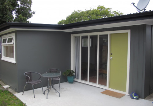 1970s home, house exterior, sleepout, grey exterior, green door, grey sleepout